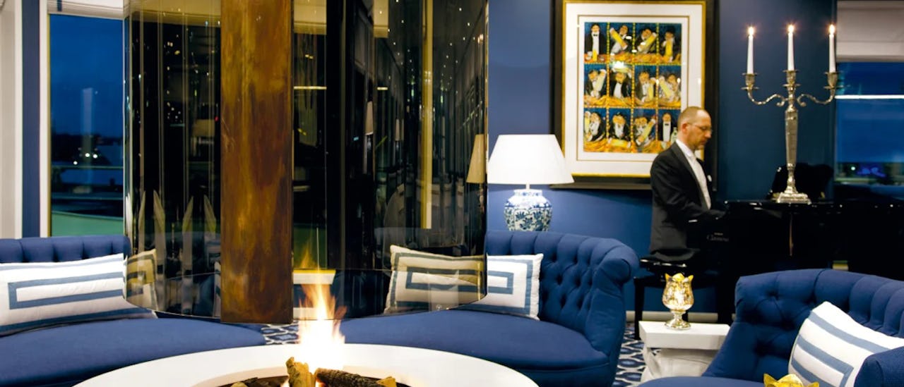 Lounge des Kreuzfahrtschiffes S.S. Bon Voyage mit Tischkamin und Klavierspieler